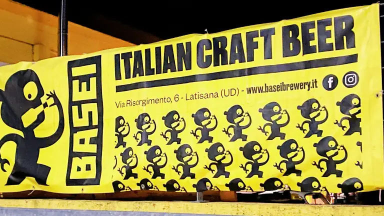 Banner con il logo del birrificio Basei a Latisana e informazioni, affisso sulla facciata esterna del locale.